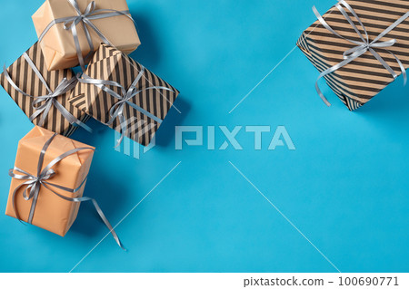 Colorful, striped and plain, brown and pink paper gift boxes tied with silver ribbons and bows on a blue background. Close-up, copy space, top view. 100690771