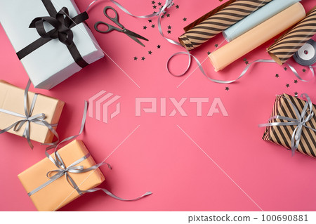 Different sizes, striped and plain, brown, rose and white paper gift boxes tied with black and silver ribbons on a pink background. Close-up, copy space, top view. Different sizes, striped and plain, brown, rose and white paper gift boxes tied with black and silver ribbons on a pink background. Close-up, copy space, top view. 100690881