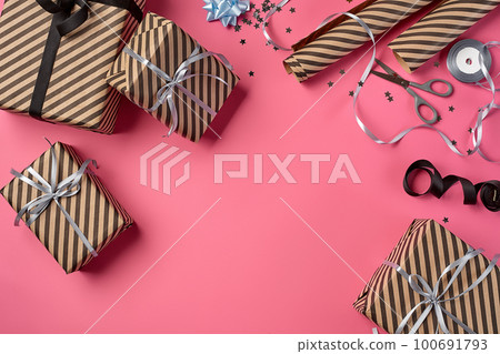 Different sizes, striped, brown gift boxes tied with black and silver ribbons and bows on a pink background. Close-up, copy space, top view. 100691793