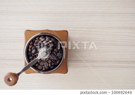 Vintage manual coffee grinder with roasted coffee beans 100692649