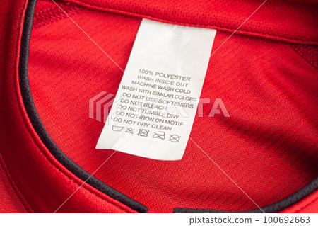 White laundry care washing instructions clothes label on red jersey polyester sport shirt 100692663