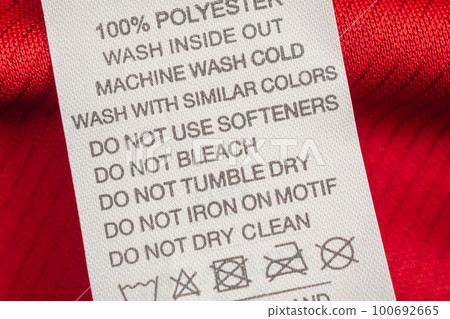 White laundry care washing instructions clothes label on red jersey polyester sport shirt 100692665