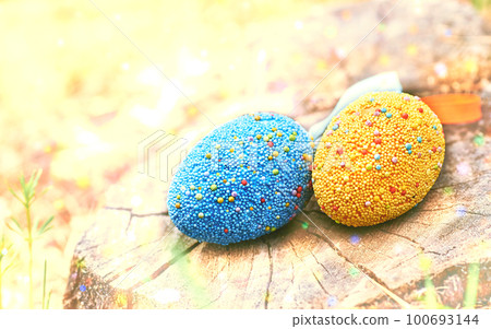 Yellow and blue Easter eggs on a stump in a haze meadow on a sunny bright day Yellow and blue Easter eggs on a stump in a haze meadow on a sunny bright day 100693144