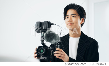Photographer shooting video with digital single lens camera 100693621