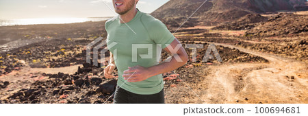 Trail run runner man training for triathlon. Banner of running athlete outdoor on mountain path. Panoramic crop of triathlete exercising cardio outdoors 100694681