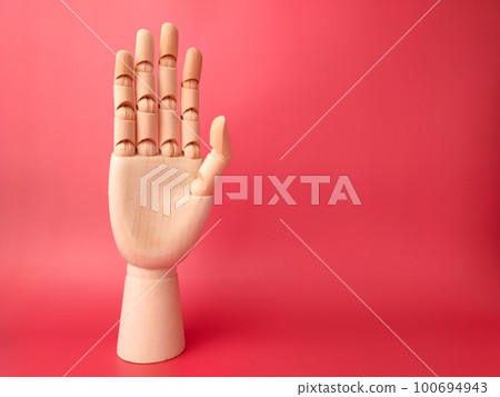 Wooden hand that is showing the style of raising hands on a red background. 100694943
