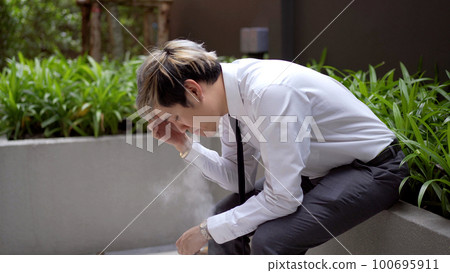 Asian white collar worker smoking an e-cigarette, alternative smoking for health. 100695911