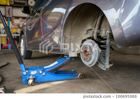 Technician or repairman using a hydraulic jack lift up a car at rear wheel to changing a flat tyre. Technician or repairman using a hydraulic jack lift up a car at rear wheel to changing a flat tyre. 100695988