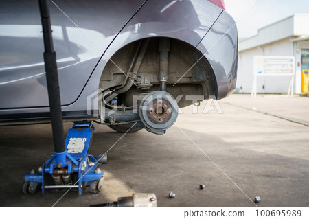 Technician or repairman using a hydraulic jack lift up a car at rear wheel to changing a flat tyre. Technician or repairman using a hydraulic jack lift up a car at rear wheel to changing a flat tyre. 100695989