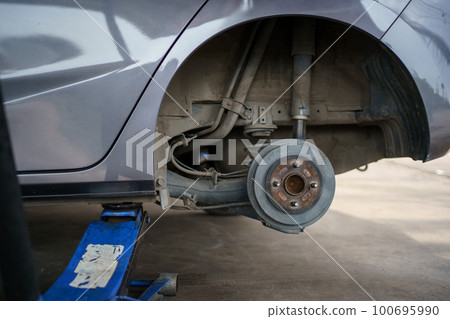 Technician or repairman using a hydraulic jack lift up a car at rear wheel to changing a flat tyre. Technician or repairman using a hydraulic jack lift up a car at rear wheel to changing a flat tyre. 100695990