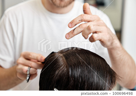Barber talking to caucasian man while sitting in chair Barber talking to caucasian man while sitting in chair 100696498