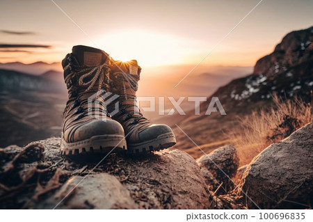 a pair of high professional boots with thick soles for walking and mountains ,stand on rocks in the mountains against , the backdrop of a beautiful sunset. 100696835
