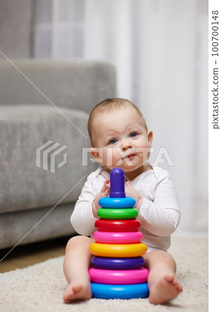 Cute baby girl playing with colorful toy pyramid Cute baby girl playing with colorful toy pyramid 100700148
