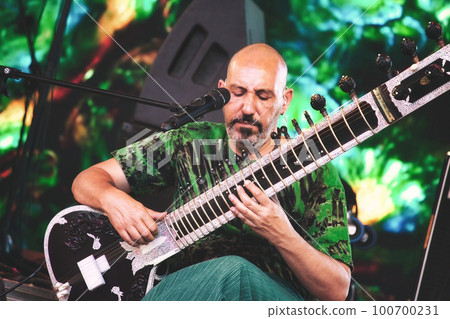 A male sitar player playing onstage at a summer festival A male sitar player playing onstage at a summer festival 100700231