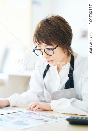 戴眼鏡的女人正在看廣告傳單 戴眼鏡的女人正在看廣告傳單 100700557