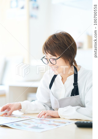 戴眼鏡的女人正在看廣告傳單 100700558