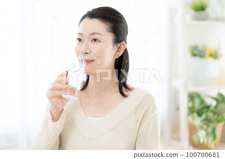 Middle-aged woman drinking mineral water 100700681