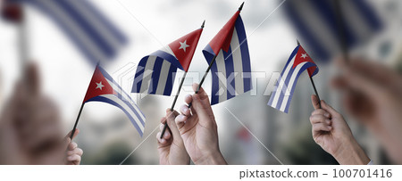 A group of people holding small flags of the Cuba in their hands A group of people holding small flags of the Cuba in their hands 100701416