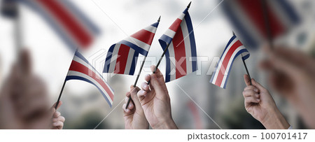 A group of people holding small flags of the Costa Rica in their hands A group of people holding small flags of the Costa Rica in their hands 100701417