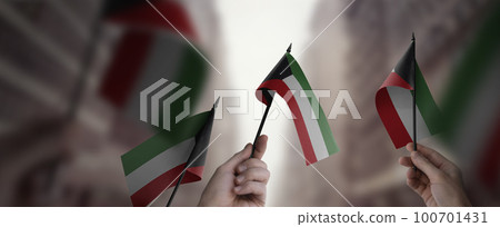 A group of people holding small flags of the Kuwait in their hands A group of people holding small flags of the Kuwait in their hands 100701431