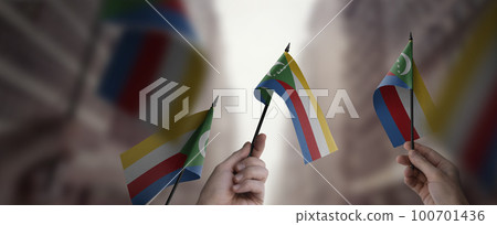 A group of people holding small flags of the Comoros in their hands 100701436
