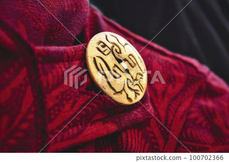 Close-up of big wooden button on the collar of an elegant red Asian style coat 100702366