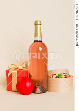 Bottle of wine on colored background for Valentine Day with gift box. Heart shaped with presrnt box perspective view with copy space 100702881