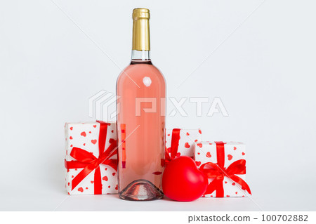 Bottle of wine on colored background for Valentine Day with gift box. Heart shaped with presrnt box perspective view with copy space 100702882