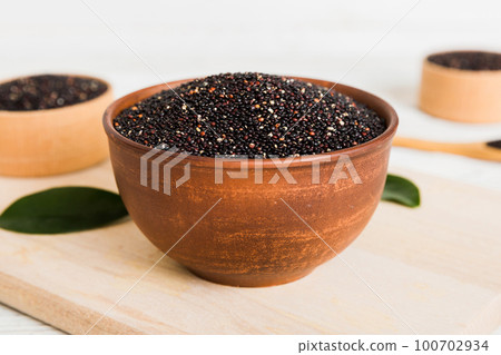 quinoa seeds in bowl on colored background. Healthy kinwa in small bowl. Healthy superfood 100702934