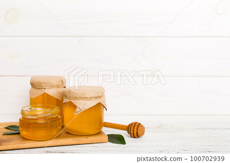 Honey in jar with leaves and honey dipper on colored background top view with copy text Honey in jar with leaves and honey dipper on colored background top view with copy text 100702939