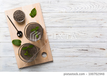 Healthy breakfast or morning with chia seeds lemon and mint on table background, vegetarian food, diet and health concept. Chia pudding with lemon and mint 100702948