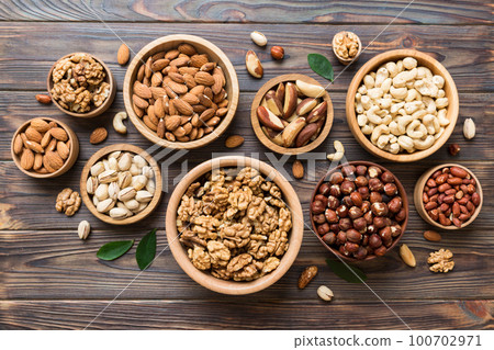mixed nuts in wooden bowl. Mix of various nuts on colored background. pistachios, cashews, walnuts, hazelnuts, peanuts and brazil nuts 100702971