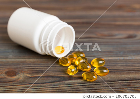Soft gels pills with Omega-3 oil spilling out of pill bottle close-up. Gel capsules bottle white surface. Omega 3, multivitamins, Calcium, antibiotics. Health. Immunity 100703703