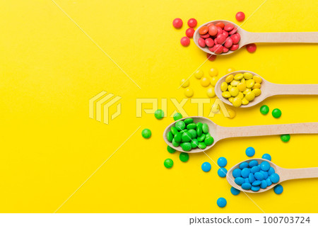 delicious colorful sweet candies on spoon on colored background . Confectionery decor top view with copy space 100703724