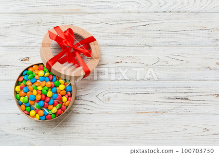 Set of different sweet candy in a paper box with a satin ribbon on a colored background. Holiday concept Set of different sweet candy in a paper box with a satin ribbon on a colored background. Holiday concept 100703730