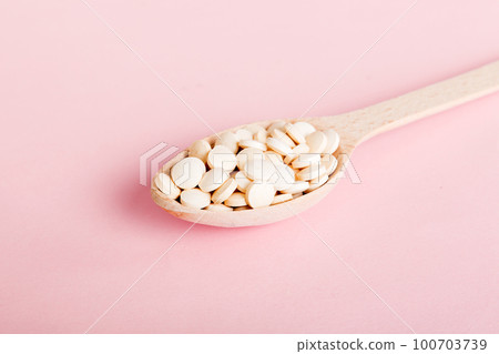 Heap of white pills on colored background. Tablets scattered on a table. Pile of red soft gelatin capsule. Vitamins and dietary supplements concept Heap of white pills on colored background. Tablets scattered on a table. Pile of red soft gelatin capsule. Vitamins and dietary supplements concept 100703739