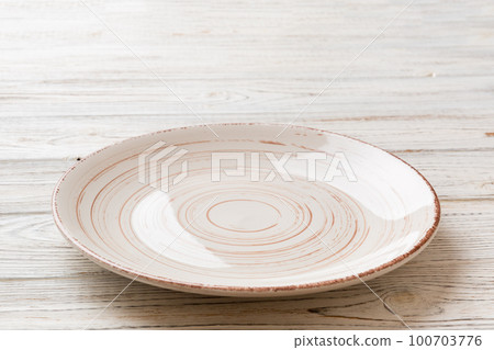 Perspective view of empty light plate on wooden background. Empty space for your design Perspective view of empty light plate on wooden background. Empty space for your design 100703776