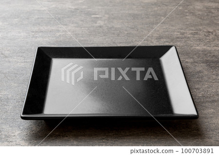 Perspective view of empty square plate on cement background. Empty space for your design 100703891