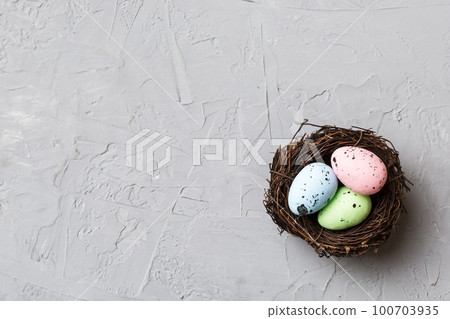 Colorful easter eggs in nest on table background with copy space top view 100703935