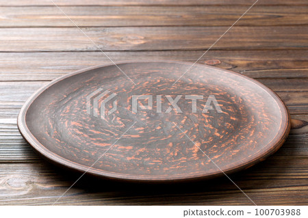 Perspective view of empty black plate on wooden background. Empty space for your design Perspective view of empty black plate on wooden background. Empty space for your design 100703988