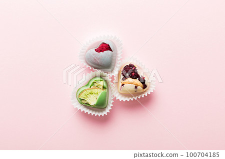 chocolate sweets in the form of a heart with fruits and nuts on a colored background. top view with space for text, holiday concept 100704185