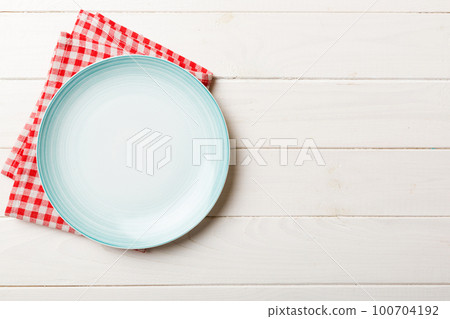 Top view on colored background empty round blue plate on tablecloth for food. Empty dish on napkin with space for your design Top view on colored background empty round blue plate on tablecloth for food. Empty dish on napkin with space for your design 100704192