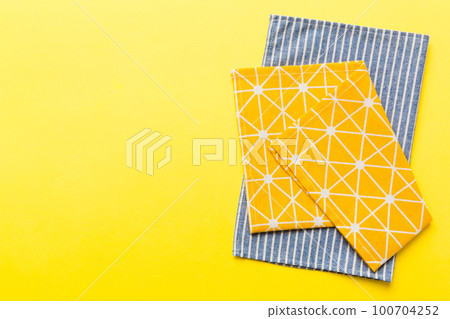 top view with yellow empty kitchen napkin isolated on table background. Folded cloth for mockup with copy space, Flat lay. Minimal style top view with yellow empty kitchen napkin isolated on table background. Folded cloth for mockup with copy space, Flat lay. Minimal style 100704252