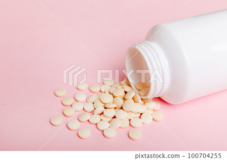 different drugs and health supplement pills poured from a medicine bottle health care and medical top view on colored background 100704255