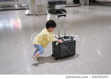 Boy pushing a suitcase Travel image 100704263