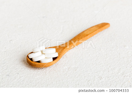 Heap of white pills on colored background. Tablets scattered on a table. Pile of red soft gelatin capsule. Vitamins and dietary supplements concept 100704333
