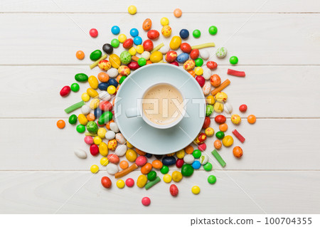 Coffee cup with chocolates and colored candy. Top view on table background with copy space 100704355