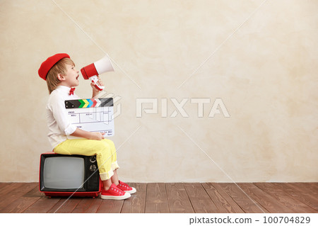 Newsboy shouting against grunge wall background. Boy selling newspaper 100704829