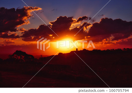 Dramatic sunset scene over hills in the countryside with deep shades of orange, red and blue Dramatic sunset scene over hills in the countryside with deep shades of orange, red and blue 100705794