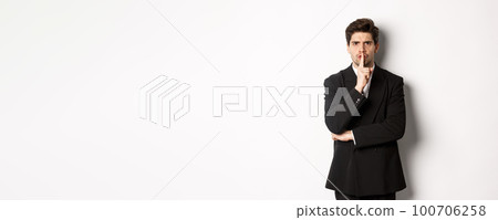 Portrait of angry boss in suit shushing at you, telling to be quiet, showing taboo hush sign and frowning, standing over white background Portrait of angry boss in suit shushing at you, telling to be quiet, showing taboo hush sign and frowning, standing over white background 100706258